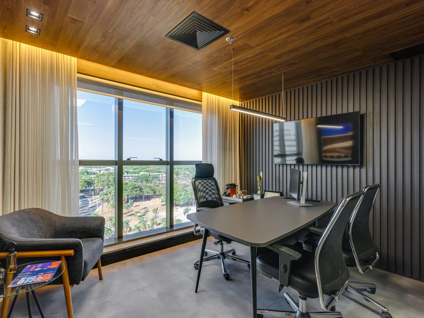 Sala com painel ripado escuro, cortina e televisão