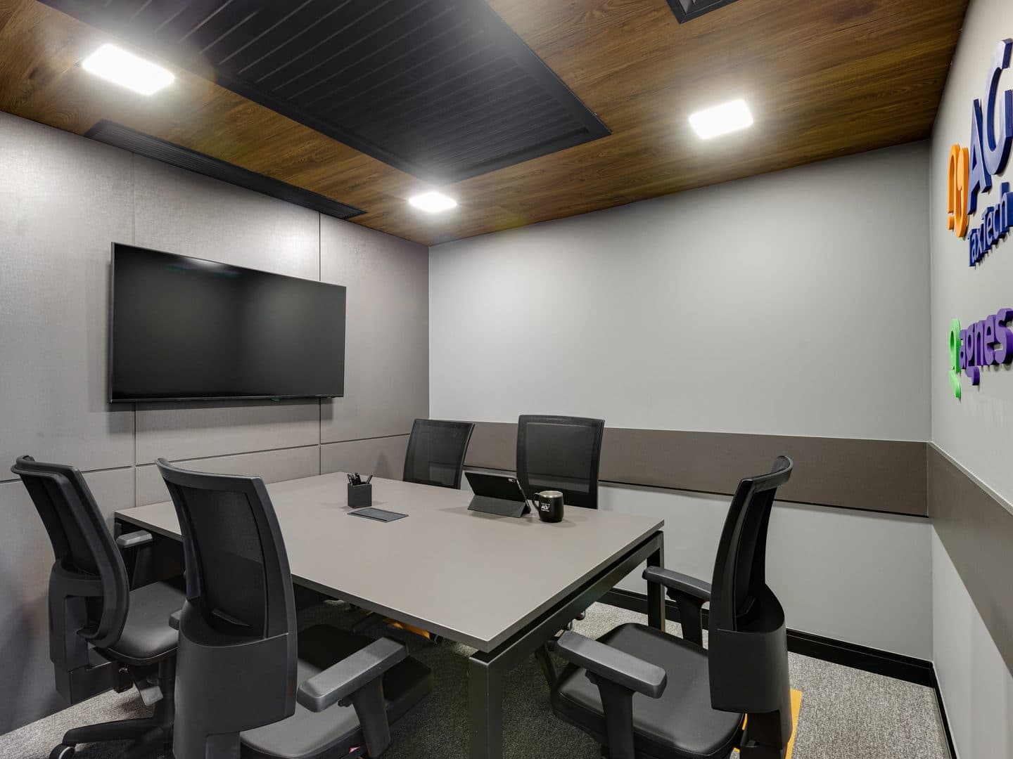 Sala de reunião interna com painéis acústicos e televisão